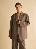 Model adjusting the lapel of the Wren boxy blazer in taupe